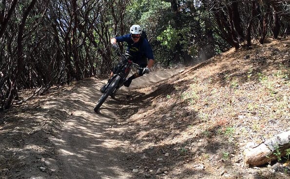 a man on a mountain bike riding down a hill on a trail